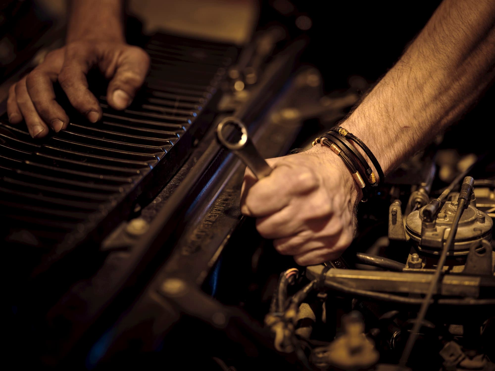 Technician working in an engine bay with a wrench during a mobile service visit